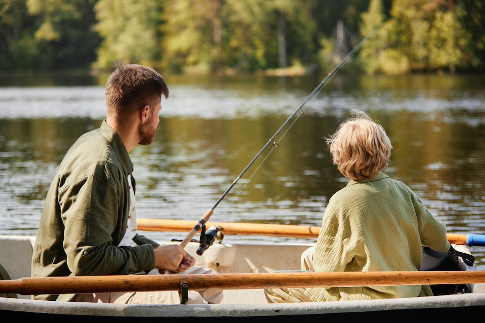 pappa och son som fiskar i en roddbåt